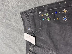 Close-up of black washed denim shorts featuring colorful rhinestones and metal stud flowers.
