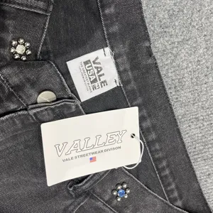 Close-up detail of dark grey denim shorts featuring colorful rhinestone floral studs and brand tags.