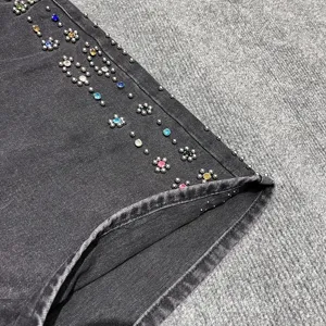 Close-up view of dark denim shorts featuring colorful rhinestones and metal stud details.