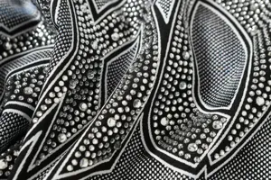 Close-up detail shot of black and white geometric rhinestone fabric, showing sparkling crystal texture.