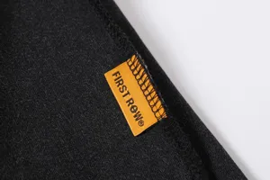 Close-up detail of black cotton t-shirt fabric featuring a distinctive orange woven brand label.