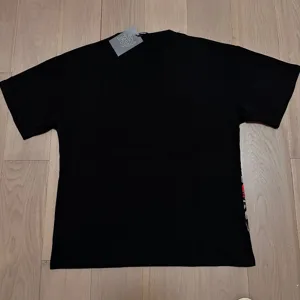 Camiseta negra de manga corta con cuello redondo y detalle grafico, moda de presentacion plana.