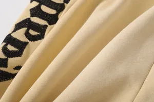 Dettaglio di pantaloncini casual lavati vintage con fascia laterale ricamata a lettere.