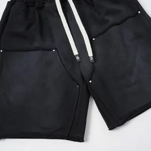 Vista dettagliata di pantaloncini streetwear neri lavati con cordini lunghi e dettagli in metallo.