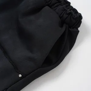 Vista dettagliata di pantaloncini neri casual con vita elastica, tasca e rivetto.