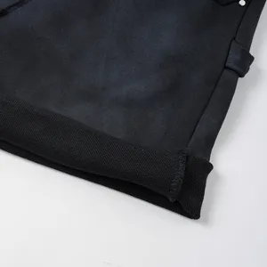 Dettaglio pantaloncini in denim lavato nero, orlo risvoltato, stile streetwear casual.