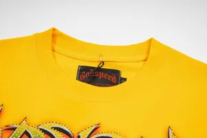 Close-up detail of yellow streetwear t-shirt collar featuring brand tag and rhinestone graphic.