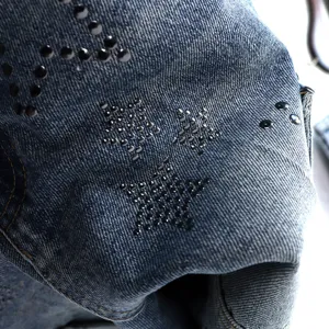 Close-up detail of denim shorts with metallic star studs, high street style fabric texture.