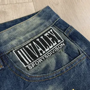 Λεπτομερης οψη τζιν ισιας γραμμης streetwear με κεντημενο εμβλημα valley sports patch.