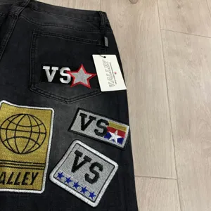 Ξeπλυμμένο μαύρο τζιν παντελόνι με κεντημένα μπαλώματα streetwear και ετικέτες λογότυπου.
