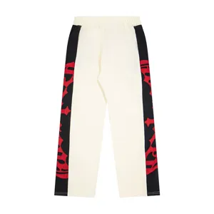 Detailed view of casual straight pants with color block sides and red cross embroidery design.