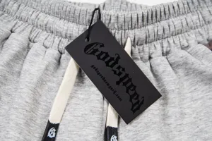 Close-up detail of grey sweatpants waistband with branded black tag and drawstring.