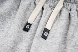 Detailed view of grey heather streetwear sweatpants with logo drawstring tips and soft fabric.