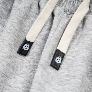 Detailed view of grey high street drawstring sweatpants with custom logo metal tips.