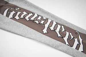 Detail of street style colorblock sweatpants with gothic embroidery lettering for daily wear.