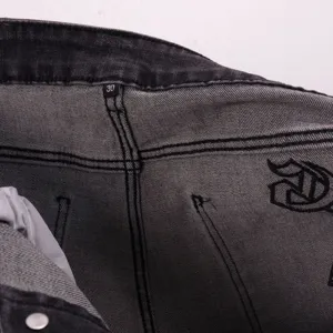 Close-up detail of gothic embroidered letter and size tag on premium denim shorts interior.