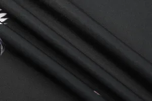 Close-up detail of black fabric texture with fine folds, soft lighting, and smooth drape.