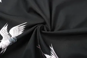 Black fabric close-up with white wing print, smooth texture detail shot for apparel design.