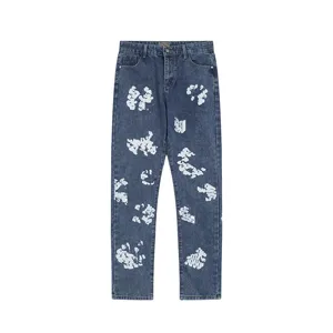 Detail view of dark blue washed denim jeans featuring unique white cotton flower all-over print.