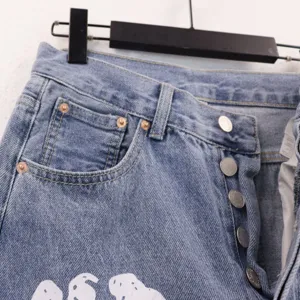 Close-up detail of light blue washed denim jeans featuring multi-button fly and metal rivets.