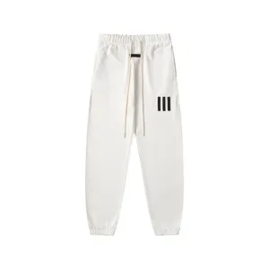 White streetwear sweatpants featuring adjustable long drawstrings and sleek tapered cuffed legs.