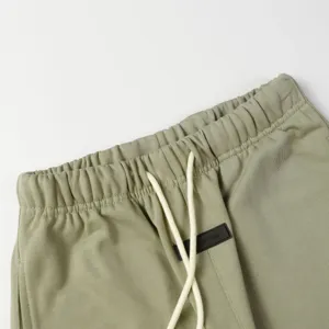Detail view of streetwear sweatpants waistband featuring adjustable drawstring and brand rubber label patch.