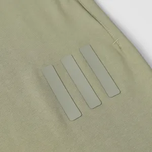 Close-up detail of casual sweatpants with rubberized bars in olive green, high street style.