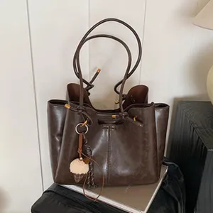 Detaillierte Ansicht der braunen Schulter-Totetasche mit großem Fassungsvermögen und Anhänger.