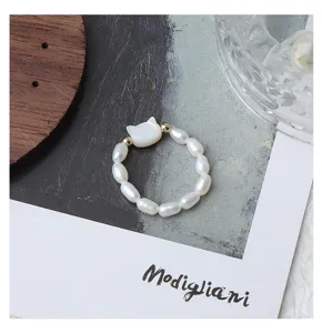 Dettaglio anello in perle d'acqua dolce con grazioso ciondolo gatto conchiglia e design elastico.