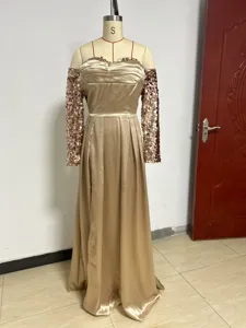 Gold evening dress detail showing sequin sleeves and off-shoulder satin bodice design.