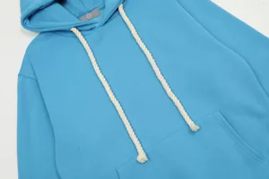 Primo piano dettagliato di una felpa con cappuccio blu vivace con cordini bianchi e tasca.