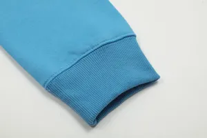 Dettaglio polsino manica felpa con cappuccio blu, tessuto a costine premium, primo piano.