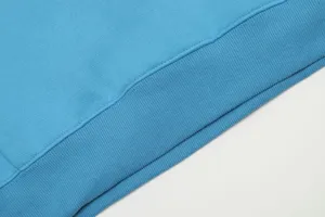 Primo piano dettagliato dell'orlo della felpa blu, con costine fini e cuciture pulite.