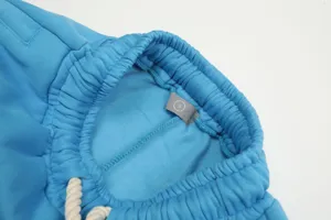 Dettaglio cintura pantaloni felpati blu, tessuto morbido, cordino e etichetta taglia.