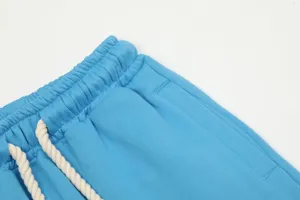 Primo piano dettagliato di pantaloni della tuta blu con elastico in vita e coulisse bianca.