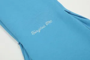 Dettaglio della manica della felpa blu con zip e testo ricamato bianco per lo streetwear.