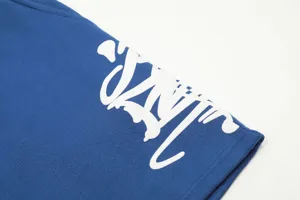 Close-up detail shot of blue streetwear shorts featuring bold white graffiti print lettering.