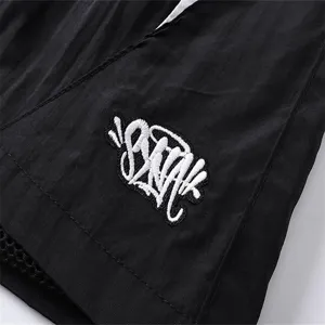 Detailed view of casual streetwear shorts featuring fine embroidery logo and durable black fabric.