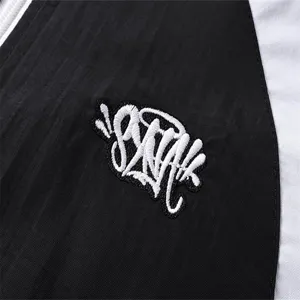 Detailed view of color block windbreaker jacket with white graffiti embroidery logo.