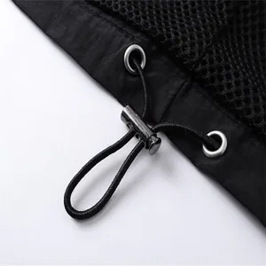 Black apparel detail closeup featuring adjustable drawstring, metal eyelets and mesh fabric.