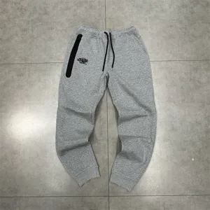 Detailed view of grey casual sweatpants featuring a black zipper pocket and custom embroidery.