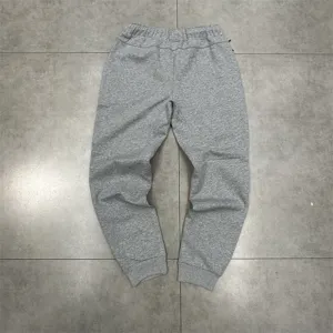 Close-up view of grey casual sweatpants with elastic cuffs and tailored paneling detail.