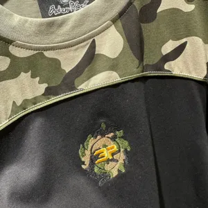 Vue détaillée du t-shirt à manches courtes camouflage streetwear avec broderie.
