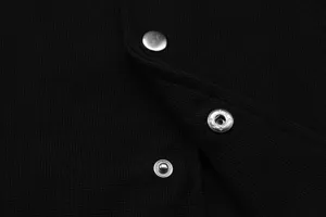 Black waffle knit fabric clothing detail showcasing metallic snap buttons texture and close-up view.