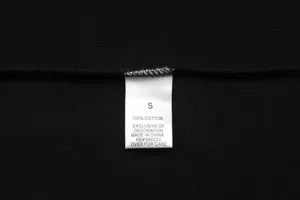 Cotton garment wash care size label detail view showing size S and material composition info.