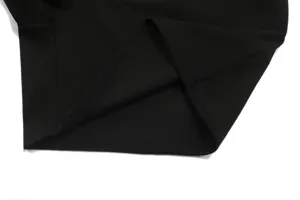 Black waffle knit fabric detail closeup showing fine hem stitching and textured surface quality.
