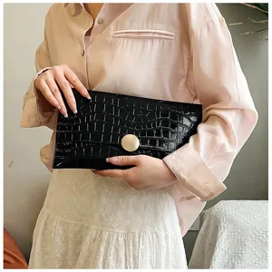 Pochette enveloppe classique en cuir vernis effet croco noir avec bouton rond doré élégant.