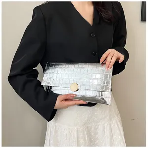 Gros plan sur les détails du sac pochette enveloppe motif crocodile en argent métallique.