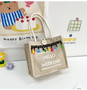 Vue détaillée du sac à main en lin stylé avec des pompons colorés et imprimé.