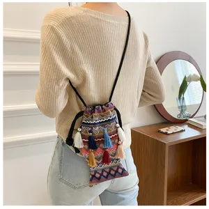 Détail de sac bandoulière ethnique tissé avec franges, motifs colorés et style bohème élégant.